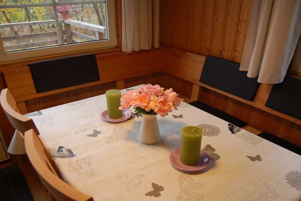 Un coin repas avec une table dressée pour deux personnes, agrémenté d’un arrangement floral et de bougies.