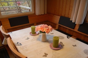 A dining area with a table set for two, featuring a floral centerpiece and candles. - Swedish house in a holiday paradise (Krakow am See)