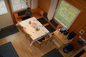 A compact room with a dining table, benches, a small kitchen area, and a window providing a view of the outdoors. - Swedish house in a holiday paradise (Krakow am See)