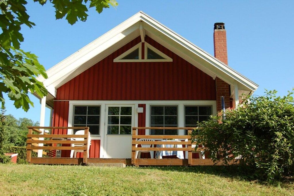 Een rood gebouw met een wit dak, een bakstenen schoorsteen en een houten hek met een bankje.