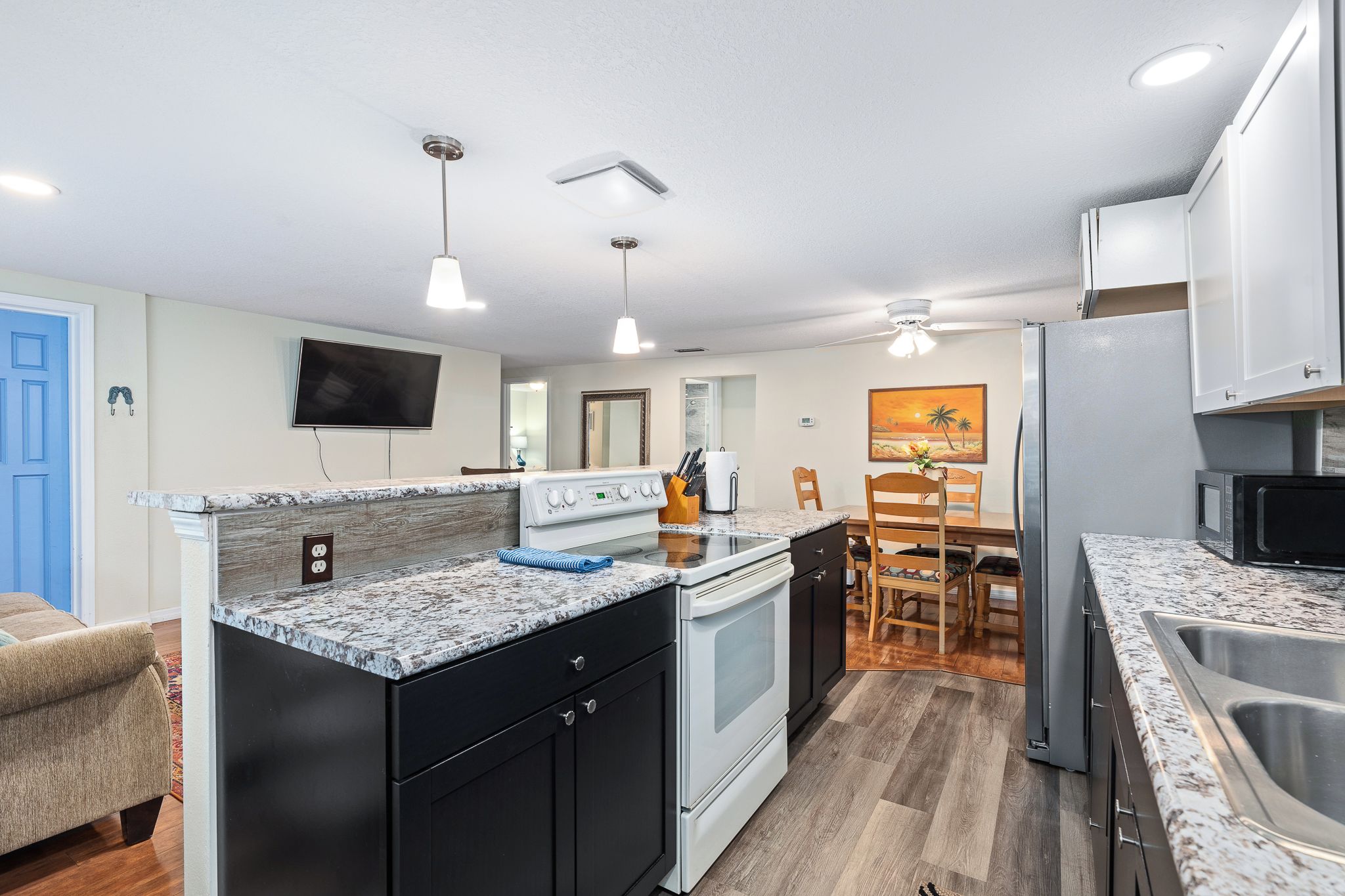 A modern kitchen with a central island, built-in oven, microwave, and stainless steel sink.