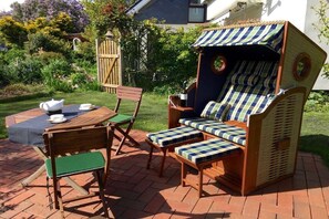 Un espace patio aménagé avec une table en bois, des chaises et un fauteuil de jardin à rayures.