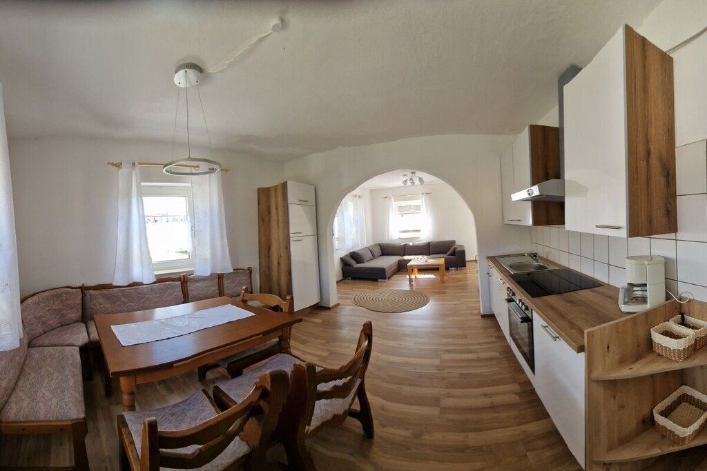 Eine moderne Küche mit Essbereich, Holzboden und Blick durch einen Bogen in ein Wohnzimmer.
