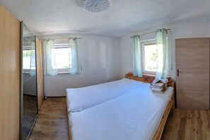 Ein Schlafzimmer mit zwei Einzelbetten, einem Holzschrank und einem Fenster mit Vorhängen.