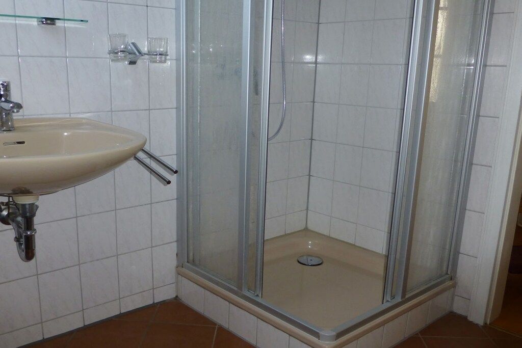 Une salle de bain avec une douche à parois de verre, un lavabo et un sol carrelé.