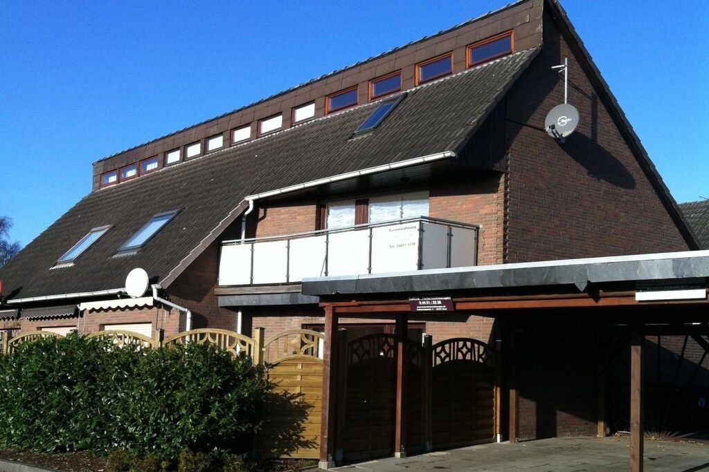 A building with a sloped roof, multiple windows, and a covered entrance area.