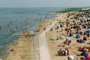 Ein voller Strand mit vielen Zelten und Menschen bei verschiedenen Aktivitäten.