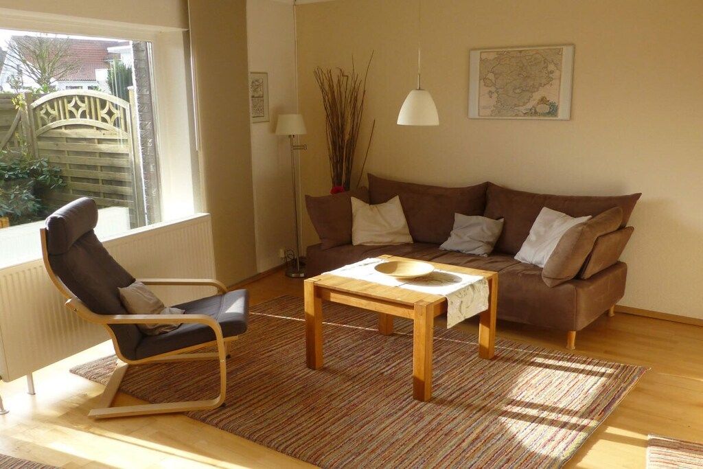 A living room with a brown sofa, a wooden coffee table, a black chair, and a floor lamp.