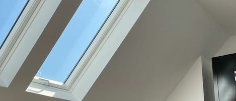 A skylight in a room with a dark-colored wardrobe and a white wall.