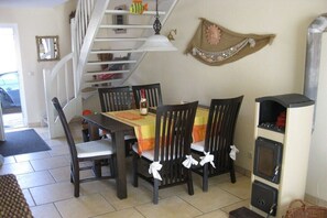 A dining area with a table set for four, a staircase, and a wall-mounted shelf with various items. - Holiday home in Pruchten with barbecue (Pruchten)