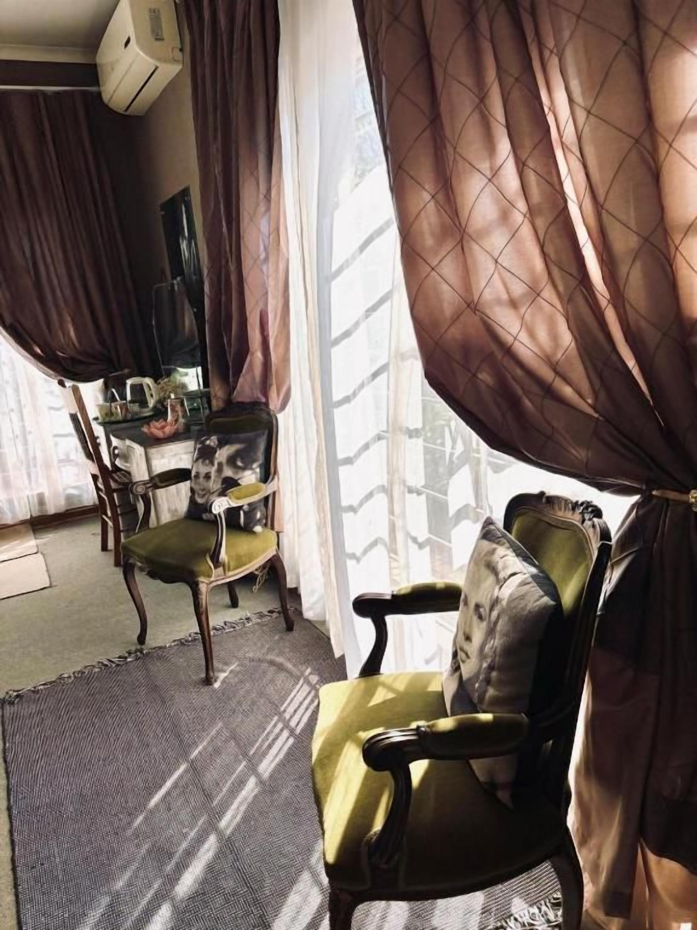 A room with a window, a chair, a table, and curtains.