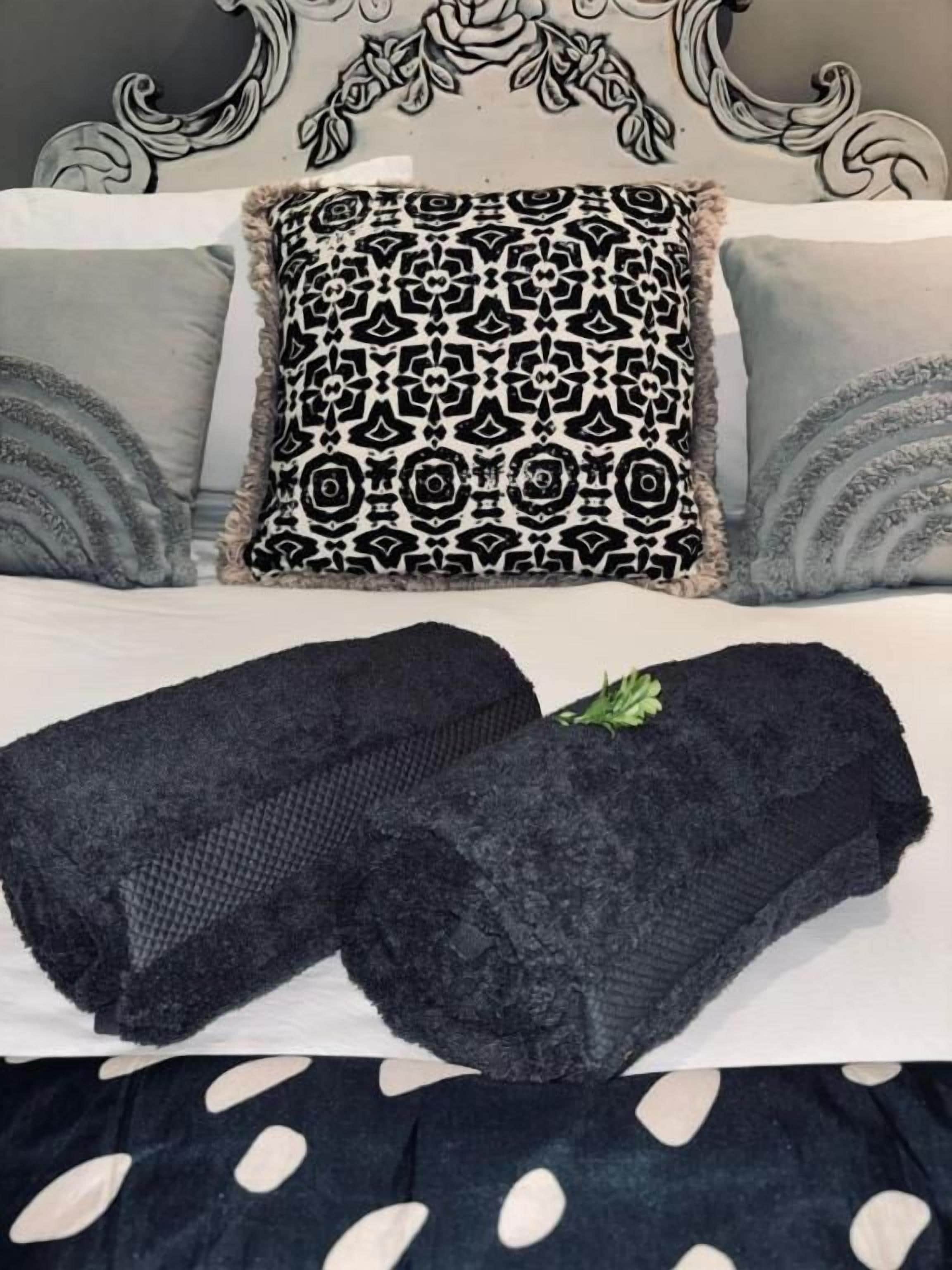 Un letto con cuscini fantasia e una coperta scura.