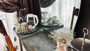 A wooden desk with a mirror, a vase with flowers, and a teapot.