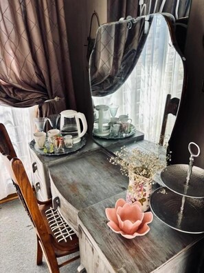 A wooden desk with a mirror, a vase with flowers, and a teapot. - LaGrace Guesthouse (Kroonstad)