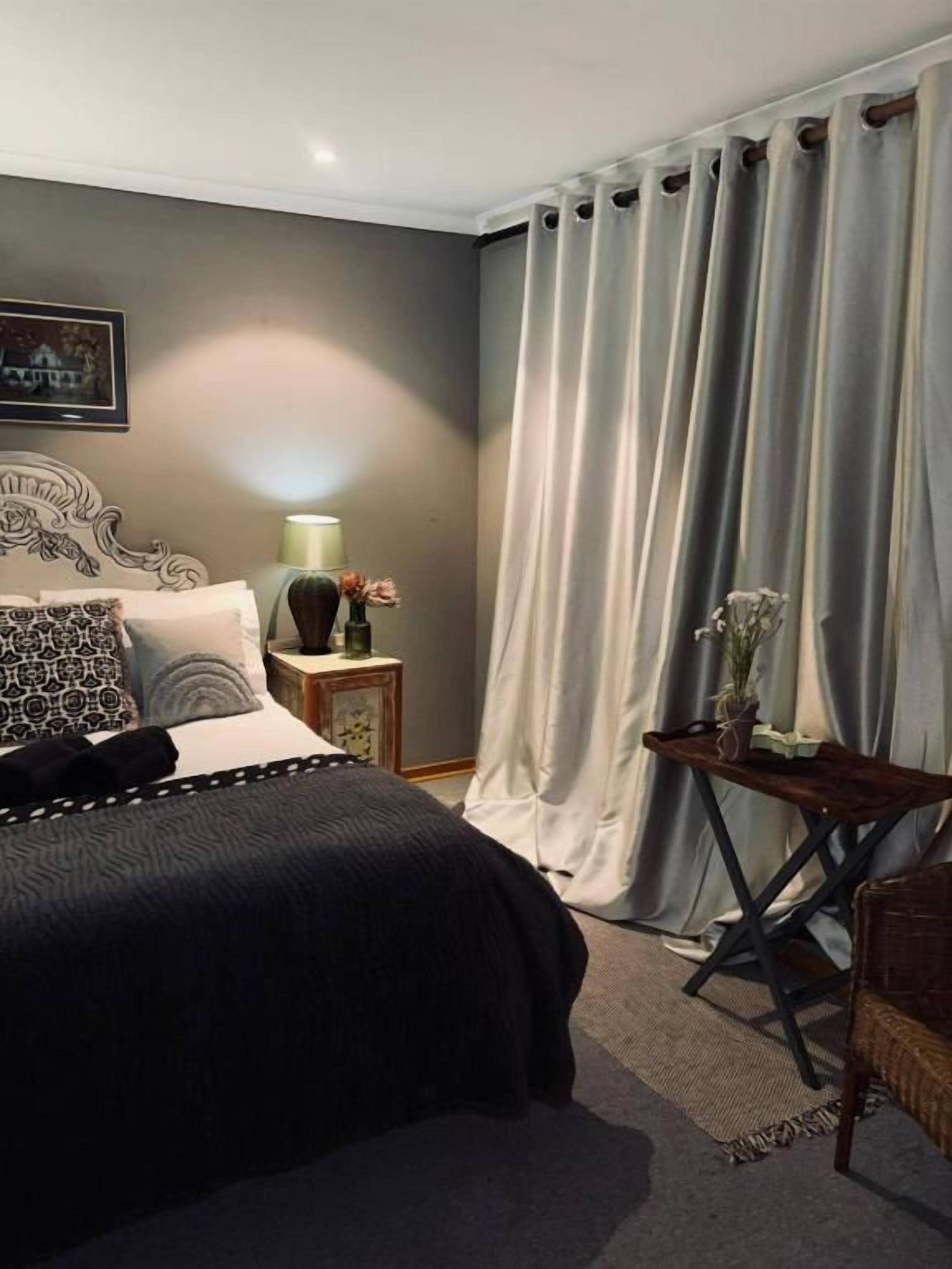 Quarto com cama, mesa de cabeceira, abajur e uma cadeira.