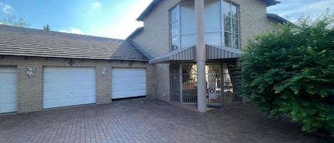 A two-story house with a garage, a paved driveway, and a fenced garden area.