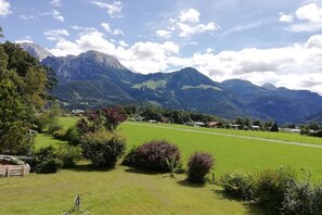 A rural landscape with mountains, a green field, and scattered houses. - Holiday apartment with 1 bedroom (Schönau am Königssee)