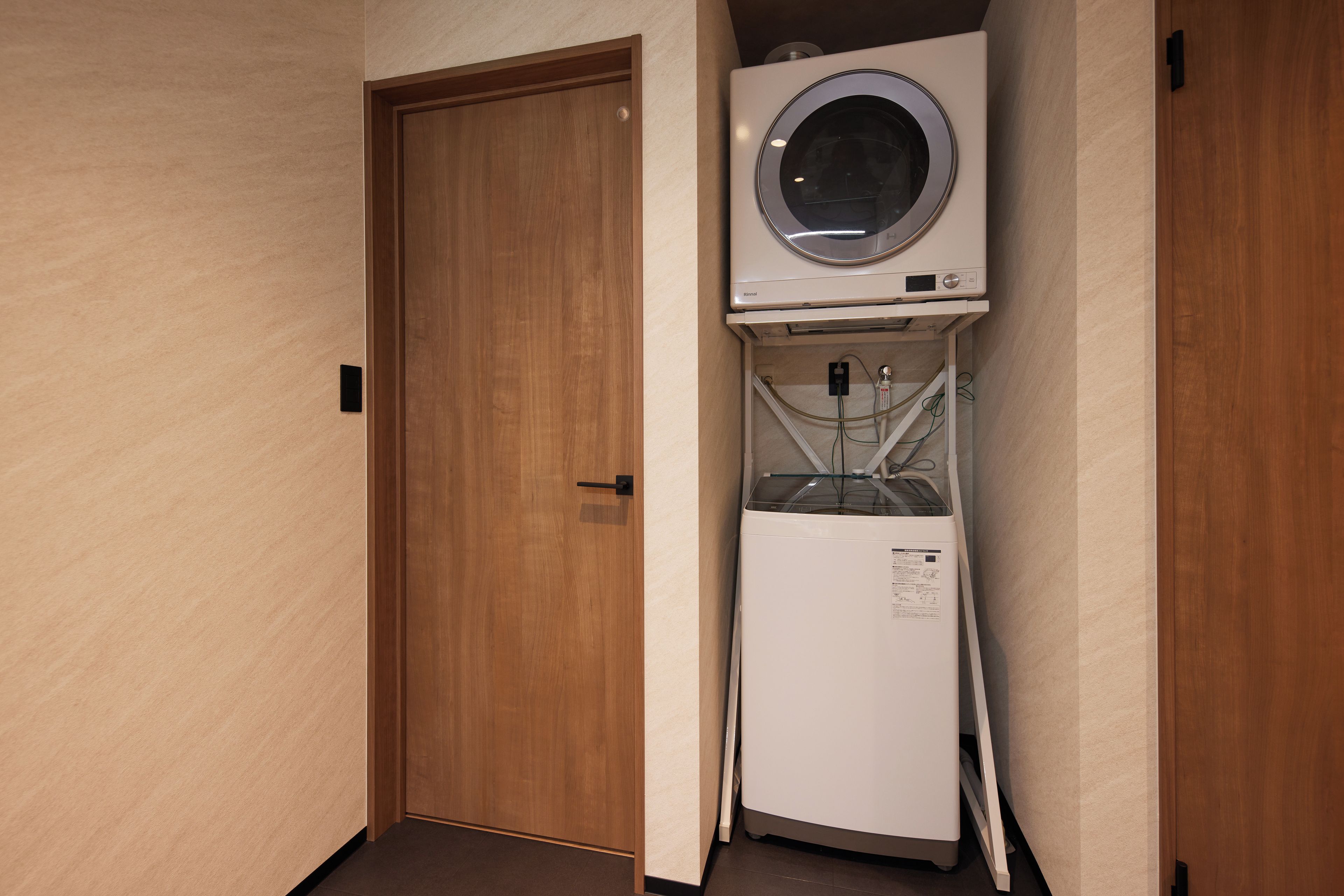 A compact room with a wooden door, a white refrigerator, and a built-in washer and dryer unit.