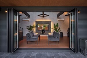 An open-plan living space with a dining area, two grey sofas, a table, and a large framed picture.