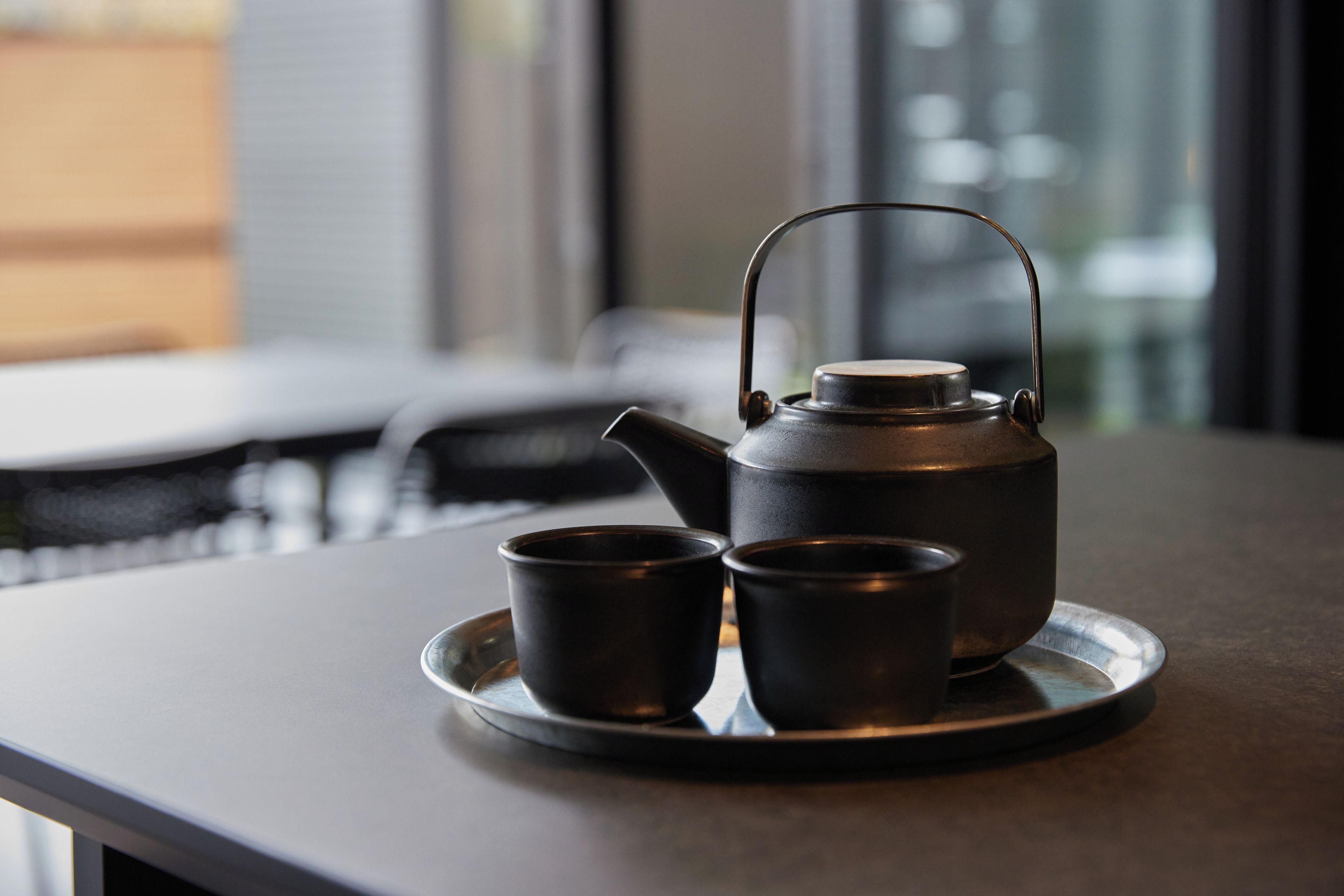 Un juego de té en una bandeja, con tetera y dos tazas, sobre una mesa.