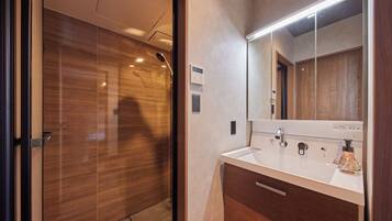 A modern bathroom with a wooden door, a white sink with a mirror, and a bottle of soap.