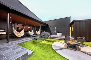 A modern outdoor patio with a grill, lounge chairs, and a hammock.