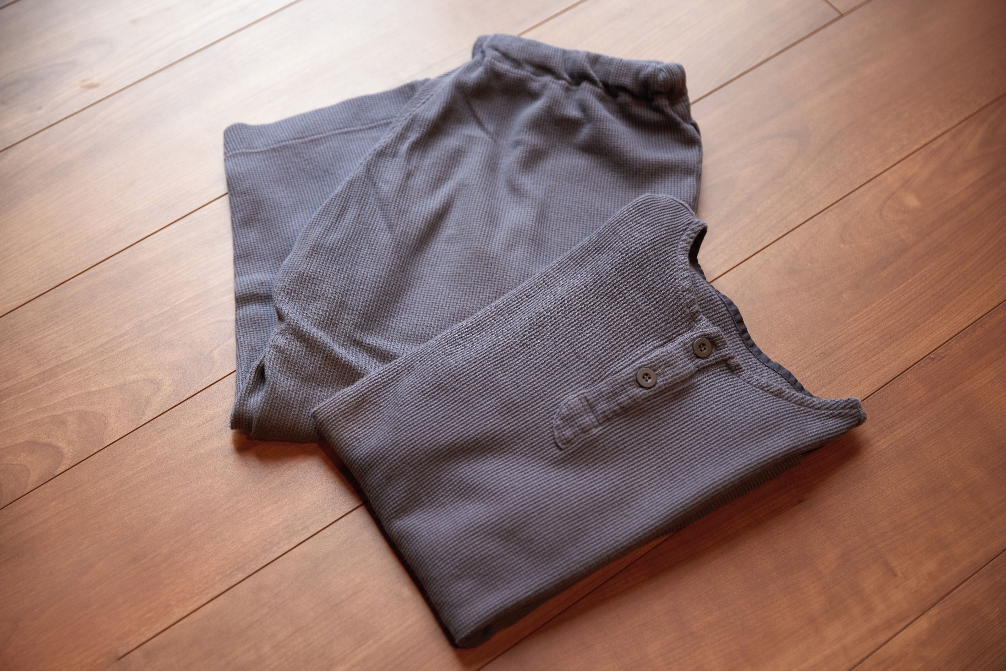 Une paire de pantalons pliés sur un plancher en bois.