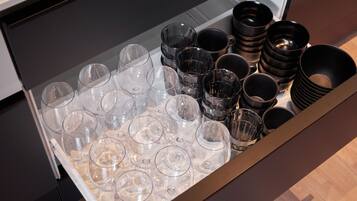 A drawer containing multiple clear wine glasses and black bowls.