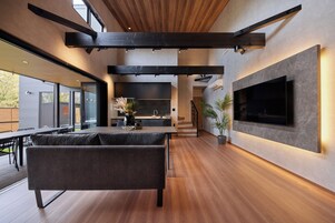 Un interior moderno con un sofá, un televisor de pantalla plana y una escalera.