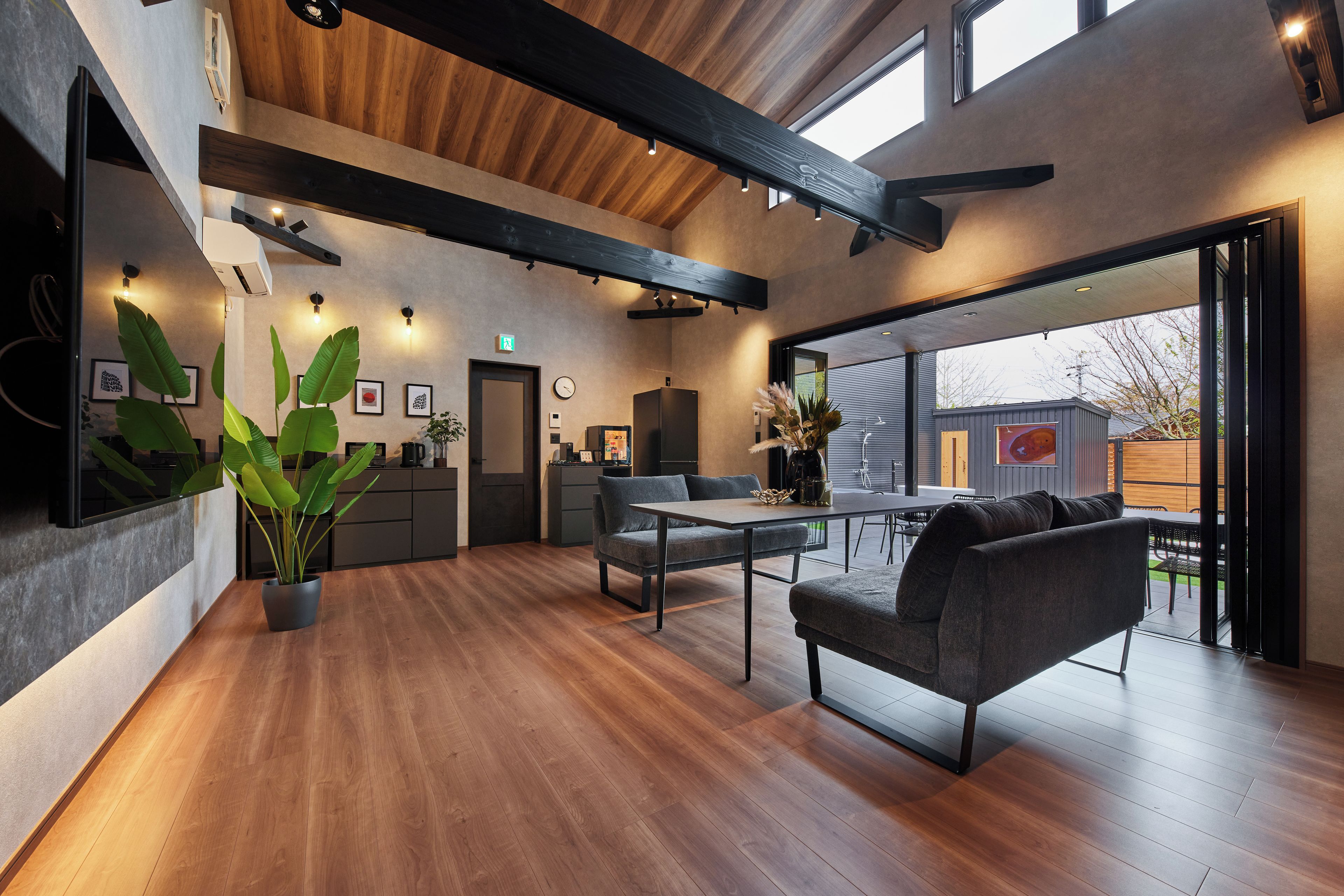 Un intérieur moderne avec un plafond en bois, un coin repas comprenant une table et des chaises, et un espace cuisine équipé de meubles et d’appareils électroménagers.