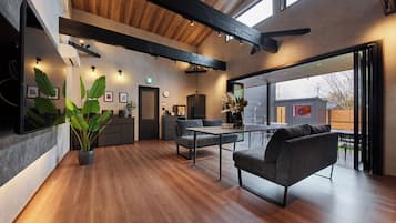 A modern interior with a wooden ceiling, a dining area with a table and chairs, and a kitchen area with cabinets and appliances.