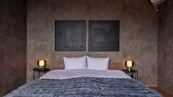 A bedroom with a large bed, two bedside tables with lamps, and abstract wall art.