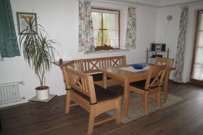 Un coin repas avec une table et des chaises en bois, une plante en pot et une fenêtre avec des rideaux.