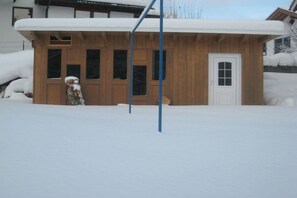 Ein Holzhaus mit verschneietem Dach und weißer Tür.