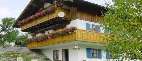 A two-story house with a balcony, a staircase, and outdoor seating.