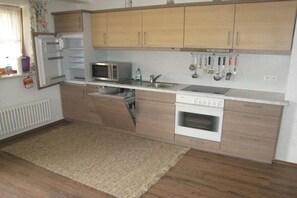 Une cuisine avec des meubles de rangement en bois, un four à micro-ondes, un évier et une cuisinière.
