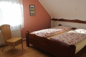 A bedroom with a wooden bed, a wicker chair, and a radiator. - at the Frank Schmidt winery (Eichstetten)