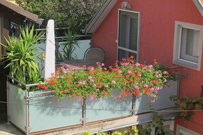 A balcony with a metal railing, a potted plant, and hanging flowers. - at the Frank Schmidt winery (Eichstetten)