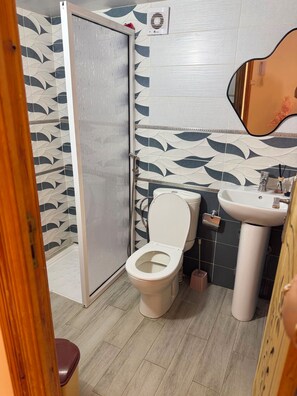 A bathroom with a toilet, sink, and shower.