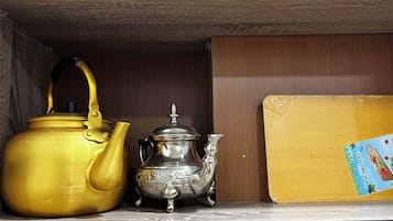 Een plank met een gouden waterkoker, een zilveren theepot en een kartonnen doos met een etiket.