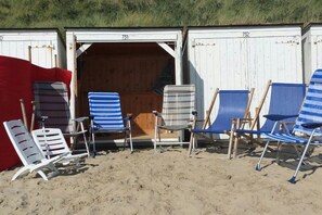 Beach chairs and a red canopy in front of a wooden structure with numbers 731 and 732. - Holiday home with 4 bedrooms (Westkapelle)