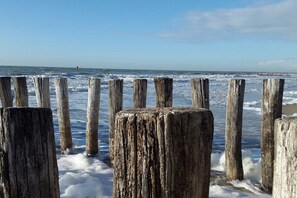 Un muelle de madera que se adentra en el océano, con olas rompiendo contra él.