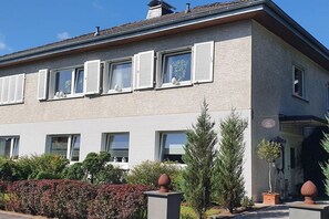A two-story building with multiple windows, a flat roof, and a small garden area with potted plants. - Holiday Lounge & Art (Bad Driburg)