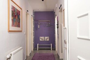 A hallway with a purple wall, a radiator, a bench, and a door on the right. - Holiday Lounge & Art (Bad Driburg)
