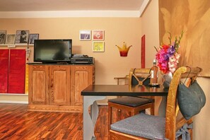 A dining area with a wooden table, chairs, and a television on a cabinet. - Holiday Lounge & Art (Bad Driburg)