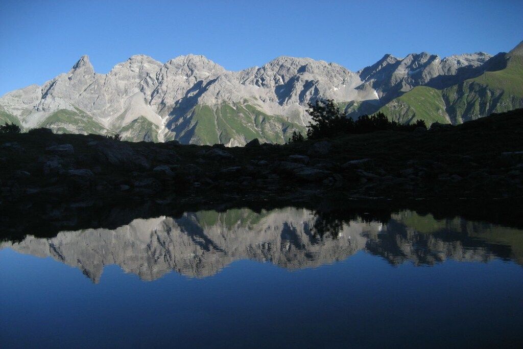 A mountain range reflected in a calm body of water.