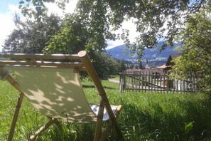 An outdoor setting with a wooden chair, a fence, and a view of a mountain landscape. - Holiday apartment with 2 bedrooms (Fischen-Au)