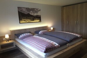 A double bed with a headboard, bedside tables with lamps, and a large wardrobe. - Holiday apartment with 2 bedrooms (Fischen-Au)