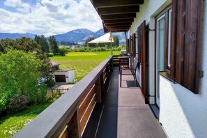 Een balkon met uitzicht op een groen veld en bergen.