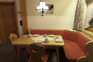 A dining area with a wooden table, heart-shaped chairs, and a red cushioned bench. - Holiday apartment with 2 bedrooms (Fischen-Au)